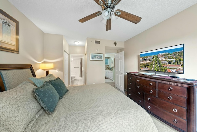 bedroom featuring ceiling fan, light colored carpet, a textured ceiling, and connected bathroom