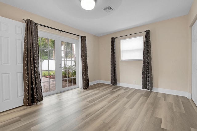 spare room featuring french doors and light hardwood / wood-style flooring