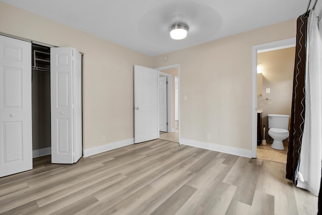 unfurnished bedroom featuring light hardwood / wood-style floors, ensuite bath, and a closet