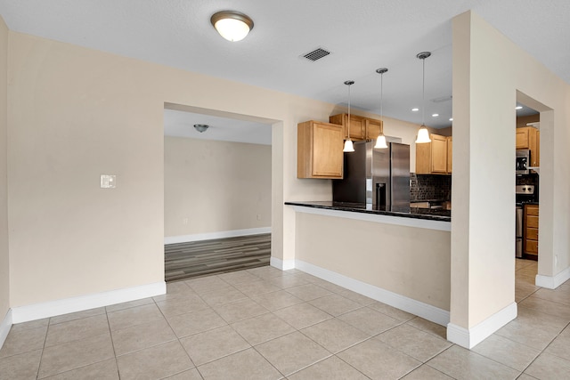 kitchen with light brown cabinets, stainless steel appliances, hanging light fixtures, and light tile patterned flooring