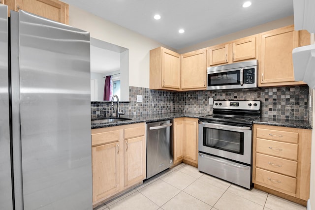 kitchen featuring decorative backsplash, appliances with stainless steel finishes, dark stone countertops, and sink