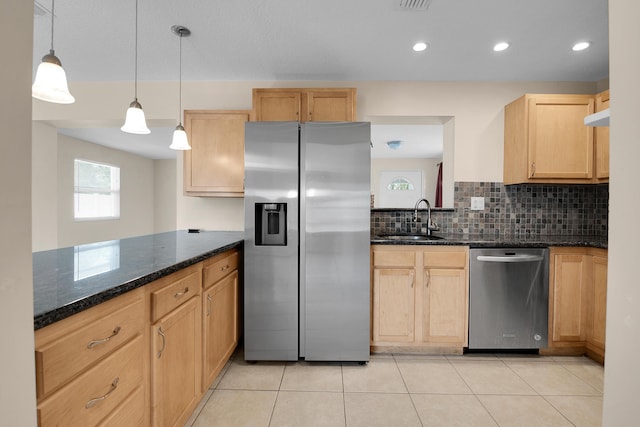 kitchen with light brown cabinets, sink, hanging light fixtures, dark stone countertops, and stainless steel appliances