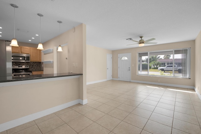 kitchen with decorative backsplash, appliances with stainless steel finishes, pendant lighting, and light tile patterned flooring