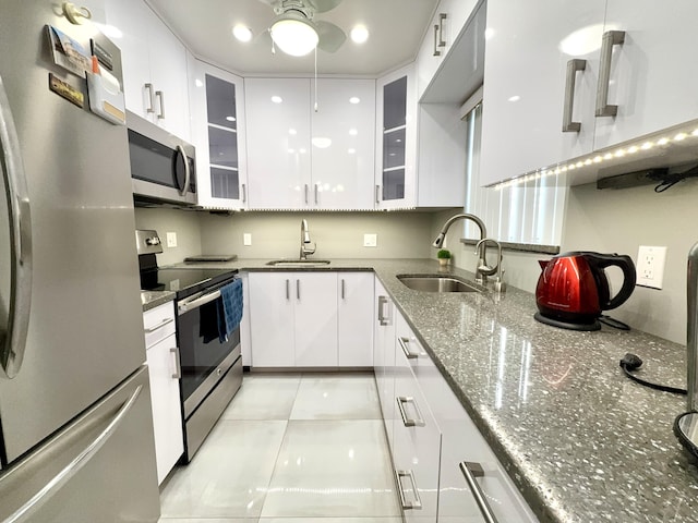 kitchen featuring appliances with stainless steel finishes, light tile patterned floors, white cabinetry, and sink