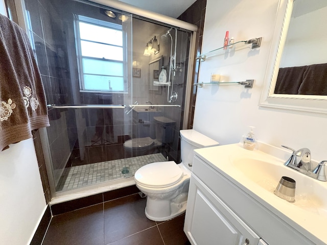 bathroom featuring tile patterned flooring, vanity, toilet, and a shower with door