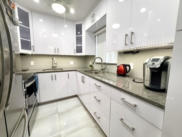 kitchen featuring stainless steel appliances, white cabinetry, dark stone countertops, and sink