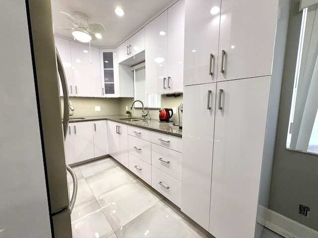 kitchen with stainless steel fridge, light tile patterned floors, white cabinetry, and sink