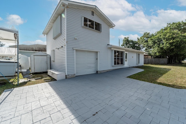 back of house with a garage, a yard, and a storage unit