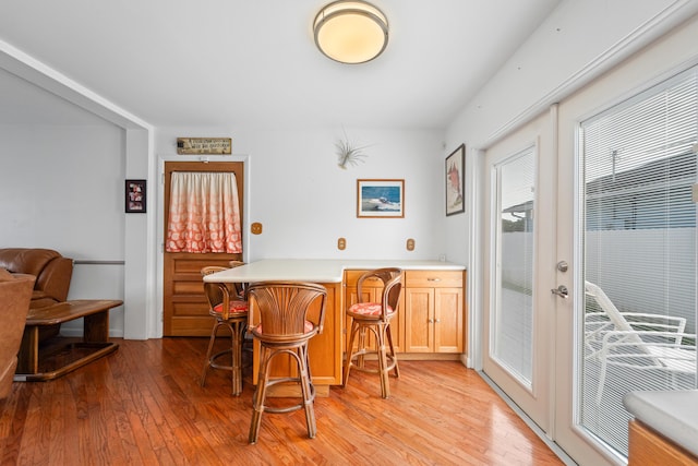 dining space with bar, light wood-type flooring, and french doors