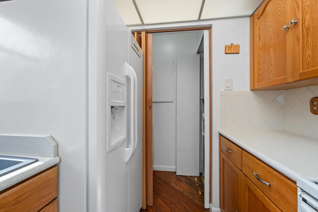 kitchen featuring dark hardwood / wood-style floors, white refrigerator with ice dispenser, and decorative backsplash