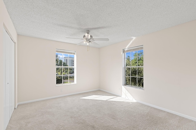 unfurnished room featuring light carpet, ceiling fan, and a textured ceiling