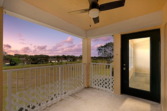 balcony at dusk featuring ceiling fan