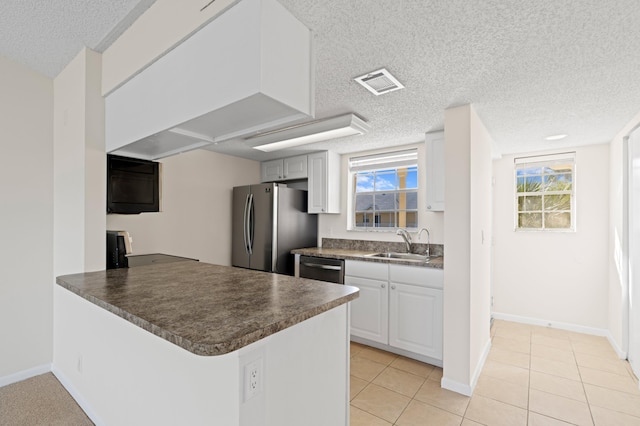 kitchen featuring kitchen peninsula, stainless steel appliances, sink, white cabinets, and light tile patterned flooring