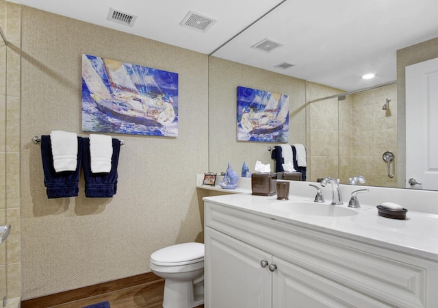 bathroom featuring hardwood / wood-style floors, vanity, toilet, and tiled shower