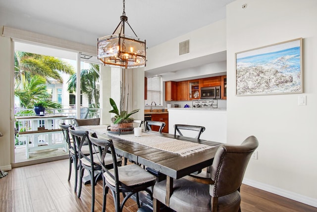 dining space featuring hardwood / wood-style flooring, sink, and an inviting chandelier