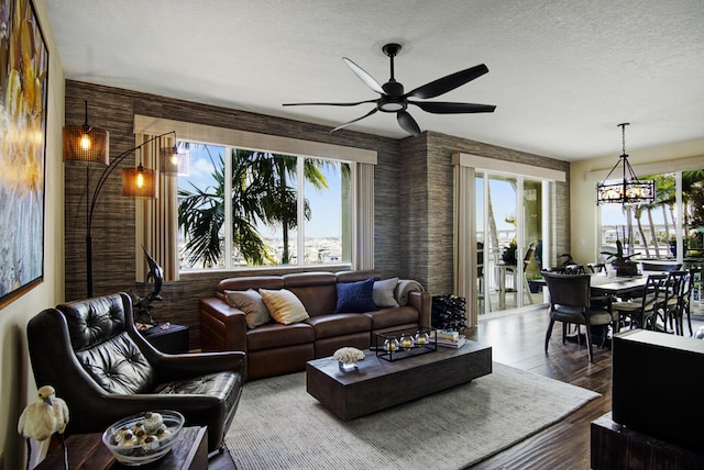 living room with plenty of natural light, ceiling fan with notable chandelier, hardwood / wood-style floors, and a textured ceiling