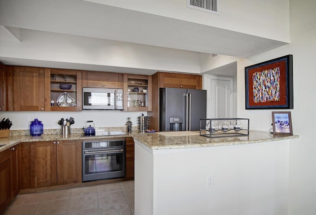 kitchen featuring light stone countertops, kitchen peninsula, stainless steel appliances, and light tile patterned floors