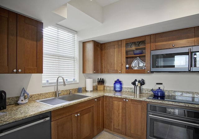 kitchen with sink, light stone countertops, and stainless steel appliances