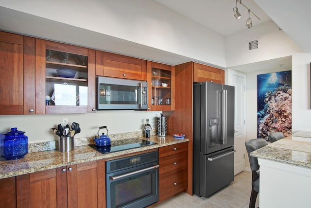 kitchen featuring appliances with stainless steel finishes, rail lighting, light tile patterned floors, and light stone counters