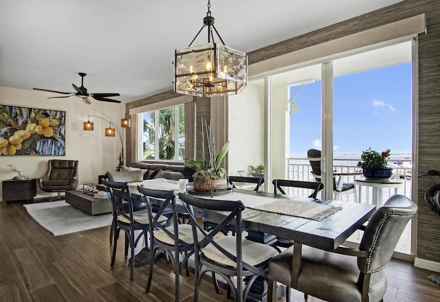 dining area featuring ceiling fan with notable chandelier and dark wood-type flooring