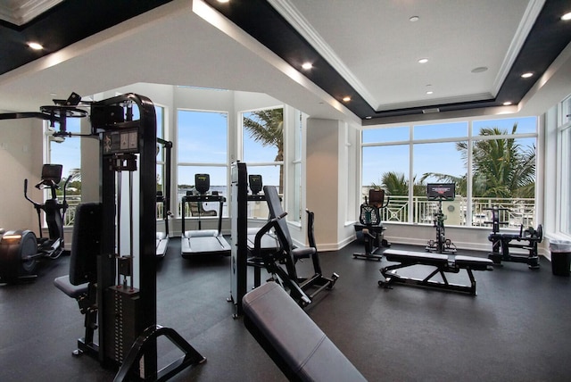 gym featuring a tray ceiling and ornamental molding