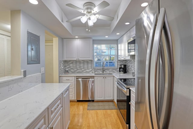 kitchen with electric panel, a raised ceiling, sink, decorative backsplash, and appliances with stainless steel finishes