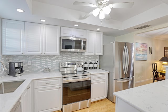 kitchen with white cabinetry, sink, stainless steel appliances, tasteful backsplash, and light wood-type flooring