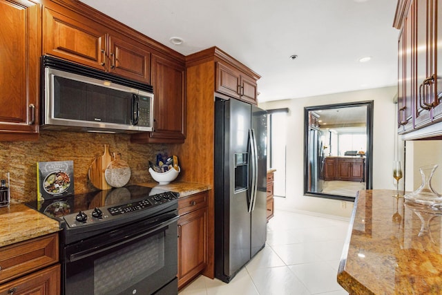 kitchen featuring tasteful backsplash, light stone countertops, light tile patterned floors, and stainless steel appliances