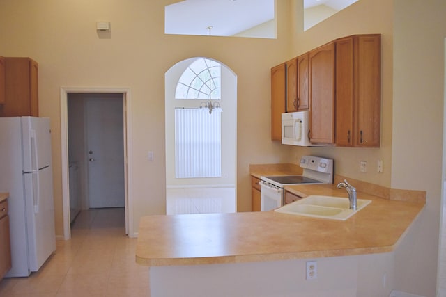 kitchen featuring vaulted ceiling, kitchen peninsula, sink, and white appliances