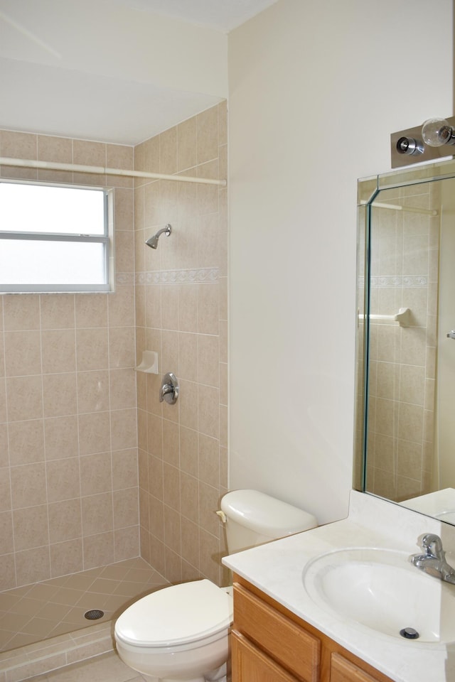 bathroom featuring a tile shower, vanity, and toilet