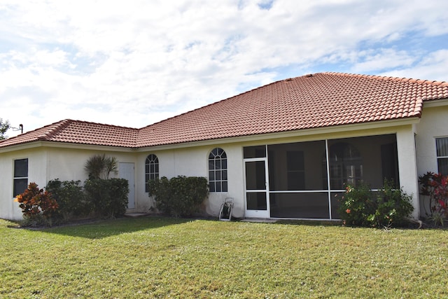 back of house with a sunroom and a lawn