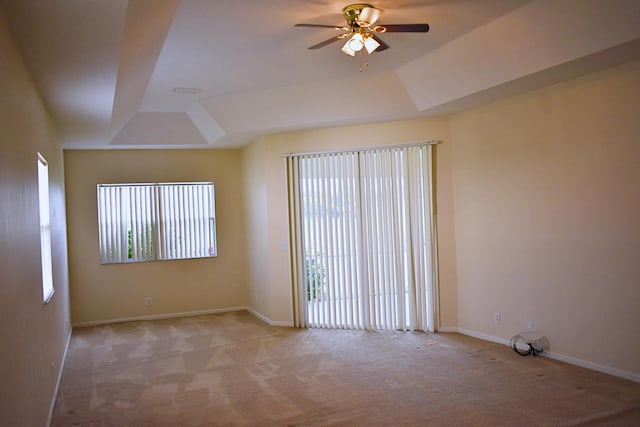 carpeted spare room featuring a raised ceiling and ceiling fan