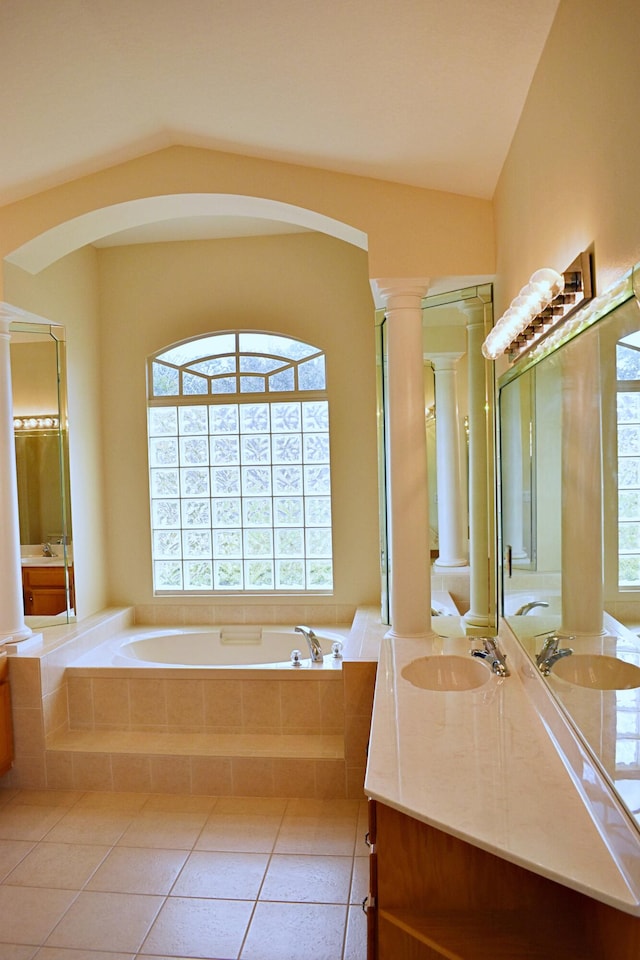 bathroom featuring ornate columns, vanity, vaulted ceiling, tile patterned flooring, and tiled bath