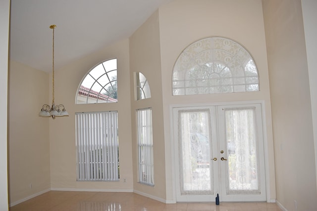 doorway with an inviting chandelier, light tile patterned floors, a high ceiling, and french doors