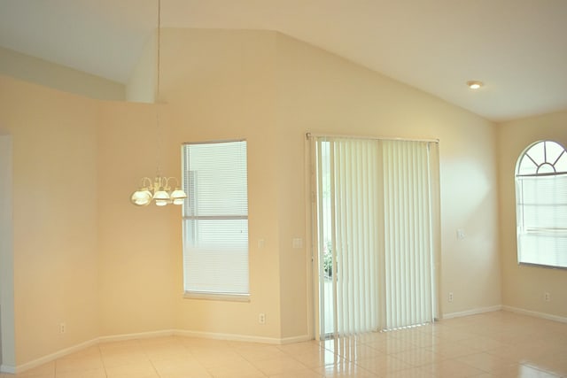 tiled spare room featuring a chandelier and vaulted ceiling