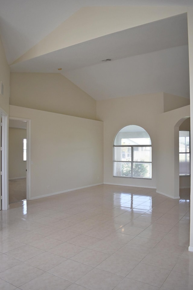 spare room featuring light tile patterned flooring and high vaulted ceiling