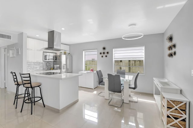 kitchen featuring white cabinets, island range hood, kitchen peninsula, and appliances with stainless steel finishes