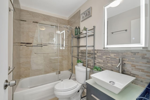 full bathroom featuring vanity, toilet, shower / bath combination with glass door, and tile walls