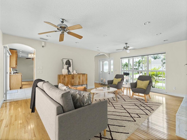 living room featuring a textured ceiling, light hardwood / wood-style floors, and ceiling fan