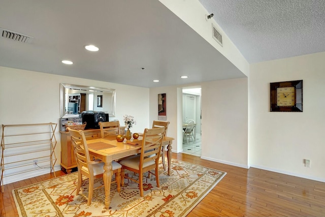 dining space with hardwood / wood-style floors and a textured ceiling