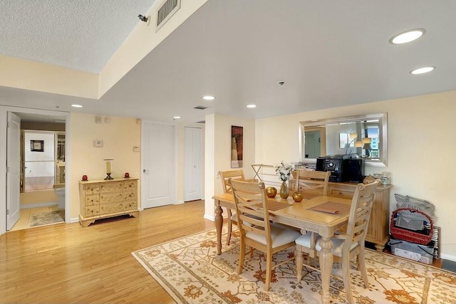 dining room with a textured ceiling and light wood-type flooring