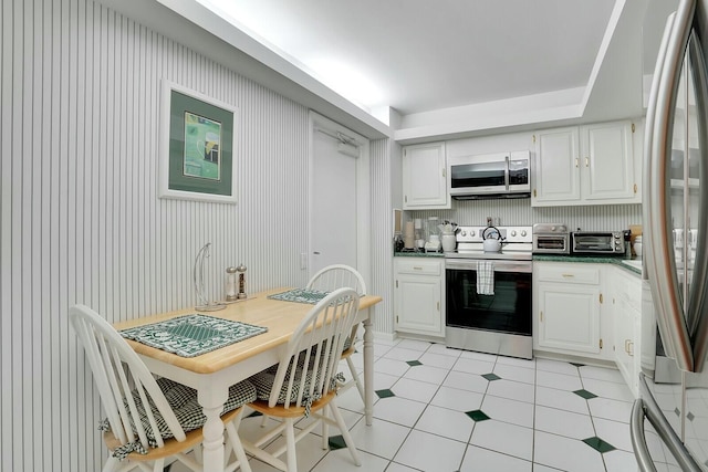 kitchen with white cabinets, decorative backsplash, light tile patterned floors, and stainless steel appliances