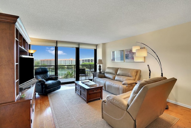 living room with a textured ceiling, light hardwood / wood-style floors, and floor to ceiling windows