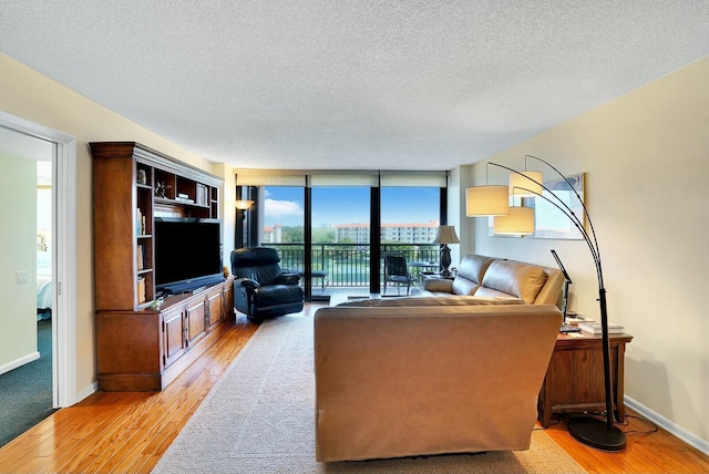 living room featuring a textured ceiling, light hardwood / wood-style flooring, and a wall of windows