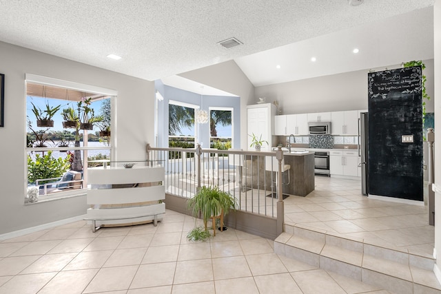 interior space with plenty of natural light, white cabinetry, stainless steel appliances, and vaulted ceiling