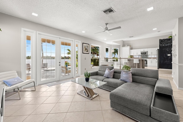 tiled living room featuring french doors, a textured ceiling, and ceiling fan