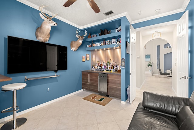 bar featuring crown molding, light tile patterned floors, a textured ceiling, and ceiling fan