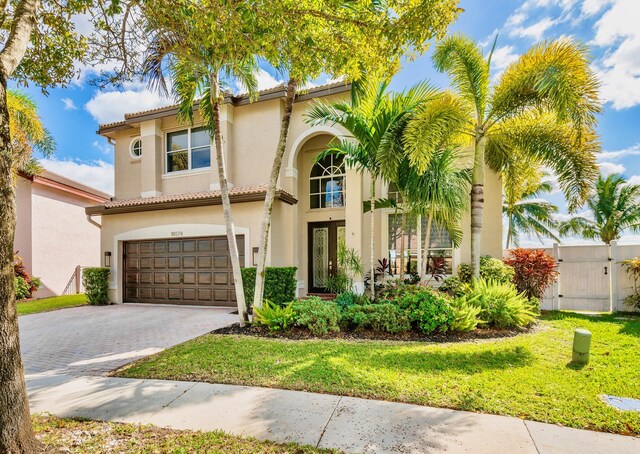 mediterranean / spanish-style home with a front yard, french doors, and a garage