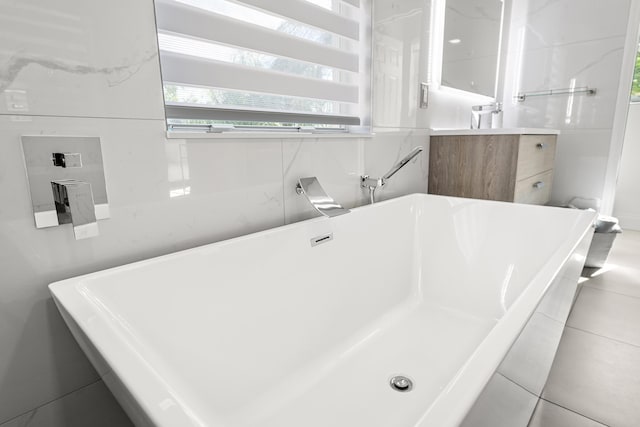 bathroom with tile patterned flooring, vanity, and a tub to relax in