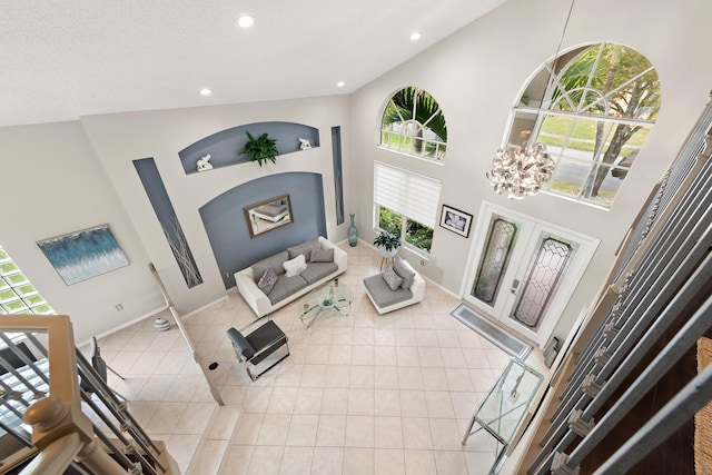 living room with a chandelier, light tile patterned floors, and high vaulted ceiling